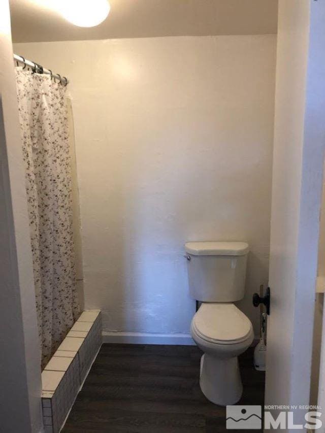 bathroom with toilet, wood-type flooring, and a shower with curtain