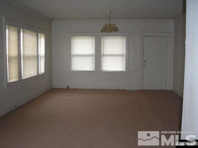 unfurnished room featuring crown molding and a chandelier