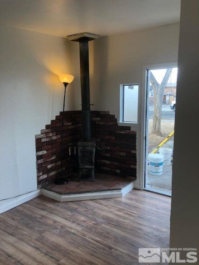 interior space with a wood stove and wood-type flooring