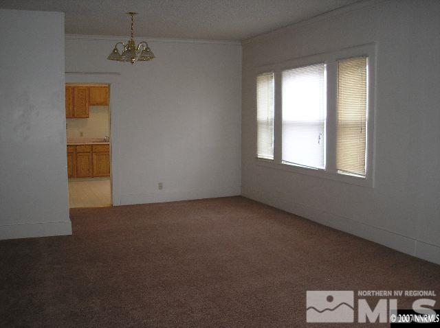 spare room with a notable chandelier, light colored carpet, and ornamental molding