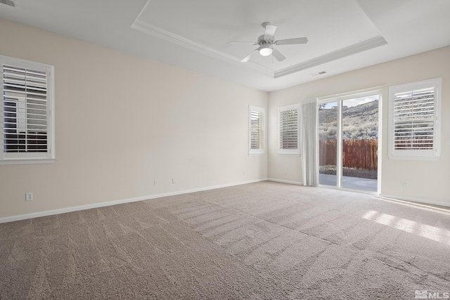 carpeted spare room with a tray ceiling and ceiling fan