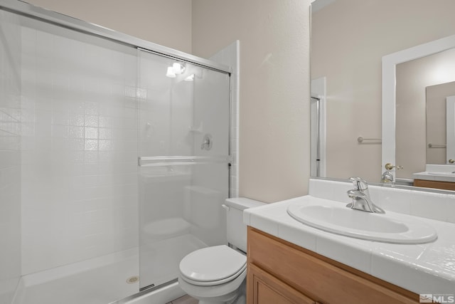 bathroom with vanity, toilet, and a shower with shower door