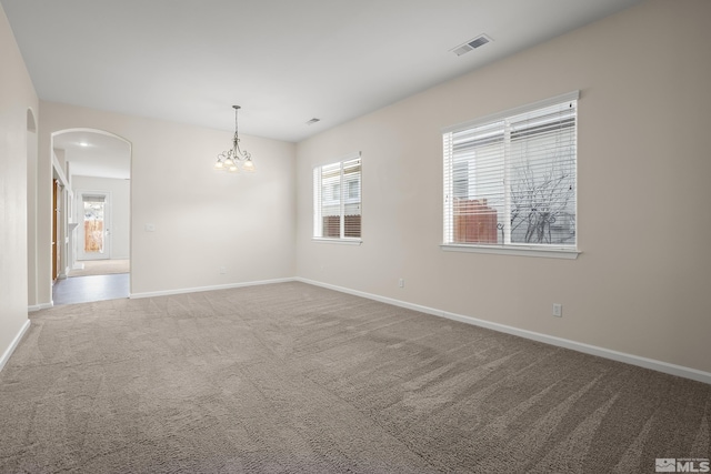 empty room featuring carpet flooring and an inviting chandelier