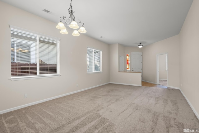 unfurnished room featuring a chandelier and light carpet