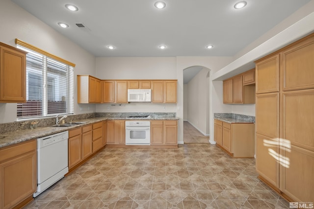 kitchen with white appliances, light stone counters, and sink