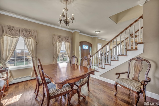 dining space with hardwood / wood-style flooring, plenty of natural light, an inviting chandelier, and ornamental molding