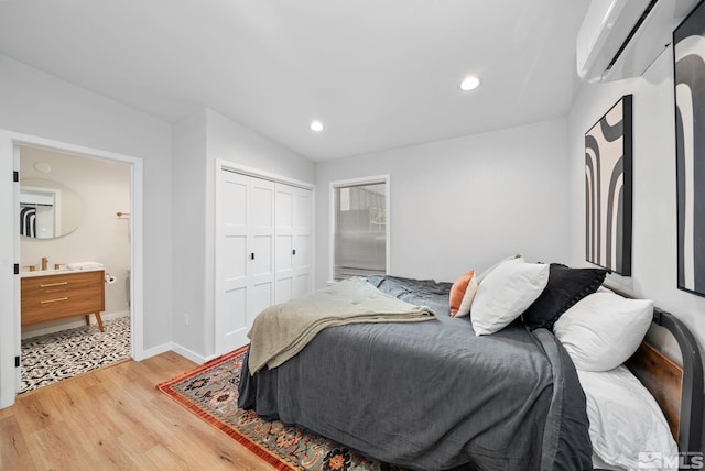 bedroom featuring light wood-type flooring, a wall unit AC, and a closet