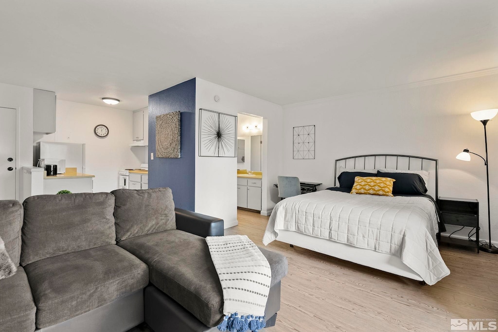 bedroom with ensuite bathroom and light hardwood / wood-style flooring