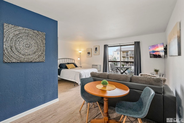 bedroom with hardwood / wood-style floors and an AC wall unit