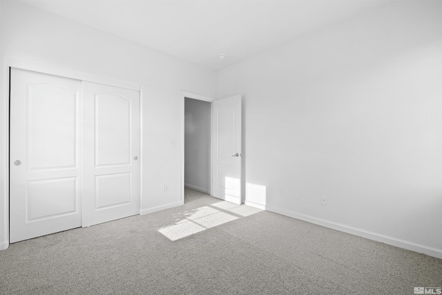 unfurnished bedroom with a closet and light colored carpet