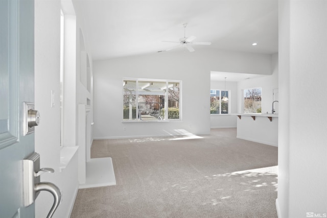 interior space featuring carpet floors, sink, ceiling fan with notable chandelier, and vaulted ceiling