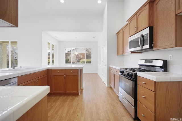 kitchen featuring hanging light fixtures, tile countertops, sink, and stainless steel appliances