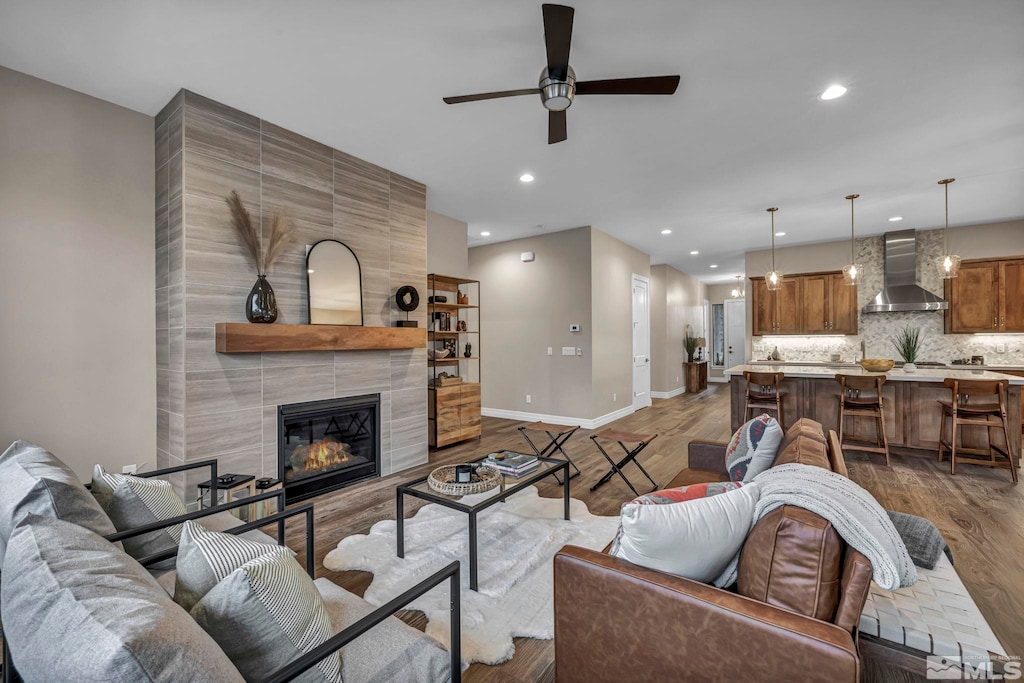 living room featuring hardwood / wood-style floors, ceiling fan, and a tile fireplace