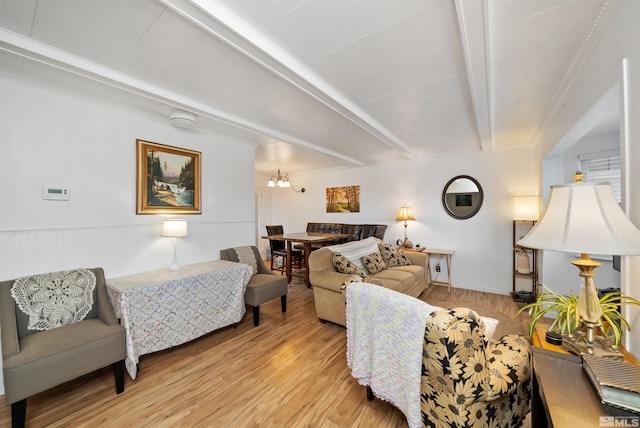 living room featuring light hardwood / wood-style flooring, beamed ceiling, and an inviting chandelier