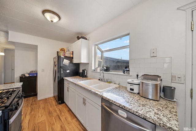 kitchen with backsplash, stainless steel appliances, sink, light hardwood / wood-style floors, and white cabinetry