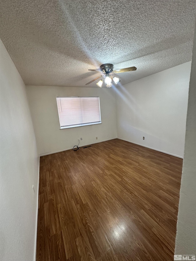 spare room with a textured ceiling and dark hardwood / wood-style floors