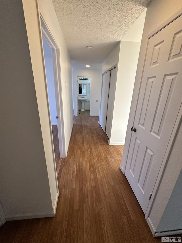 hall featuring sink, a textured ceiling, and dark wood-type flooring