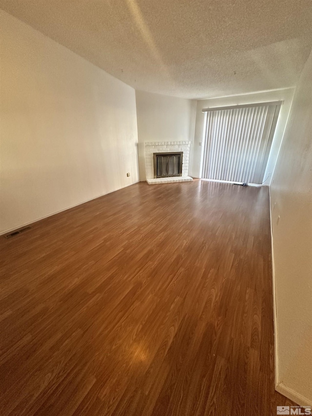 unfurnished living room featuring a textured ceiling, dark hardwood / wood-style flooring, and a fireplace