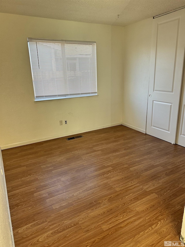 spare room featuring a textured ceiling and hardwood / wood-style flooring