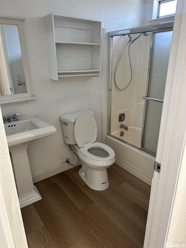 bathroom featuring hardwood / wood-style floors, toilet, and shower / bath combination with glass door