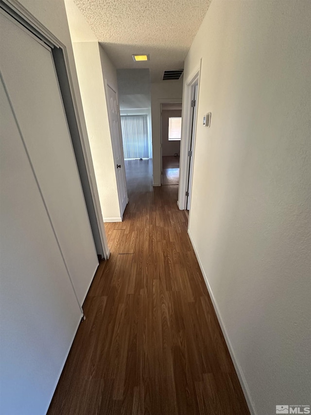 corridor featuring dark hardwood / wood-style floors and a textured ceiling