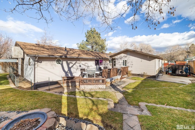 back of property featuring a fire pit, a deck, and a lawn