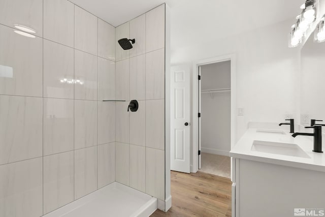 bathroom with hardwood / wood-style flooring, vanity, and a tile shower