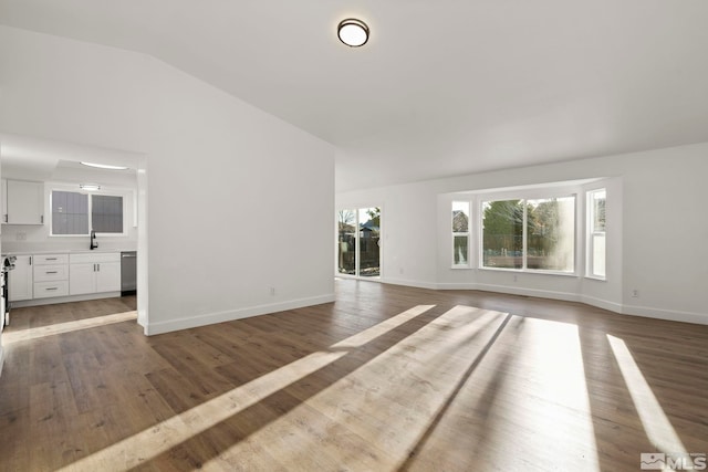 unfurnished living room with hardwood / wood-style floors, sink, and vaulted ceiling