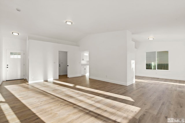 unfurnished living room featuring lofted ceiling and wood-type flooring