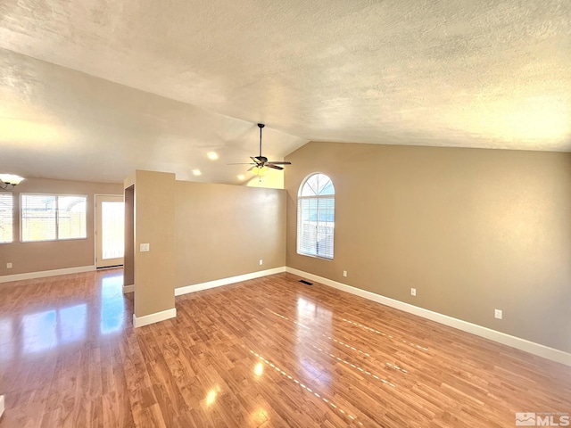 spare room with ceiling fan, lofted ceiling, a wealth of natural light, and light hardwood / wood-style flooring