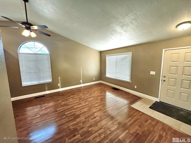 foyer featuring a textured ceiling, ceiling fan, wood-type flooring, and vaulted ceiling