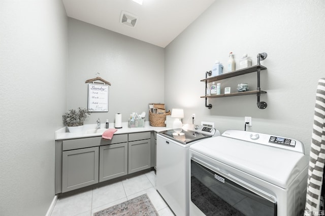 laundry area featuring washer and dryer, light tile patterned floors, and cabinets