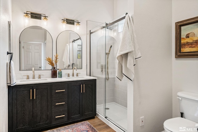 bathroom with wood-type flooring, vanity, toilet, and a shower with shower door