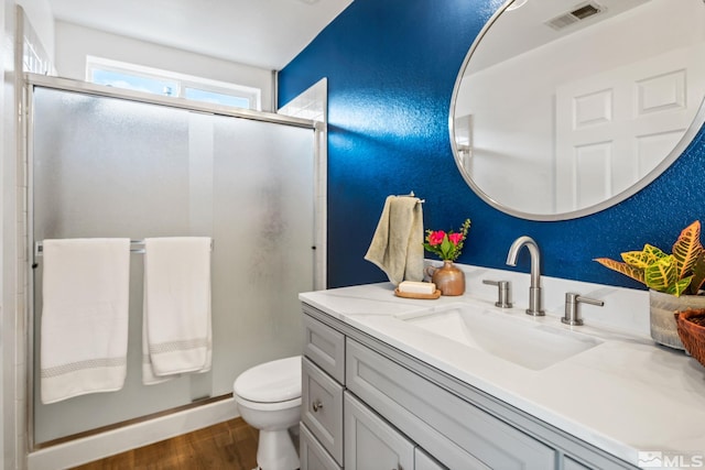 bathroom featuring a shower with door, vanity, wood-type flooring, and toilet