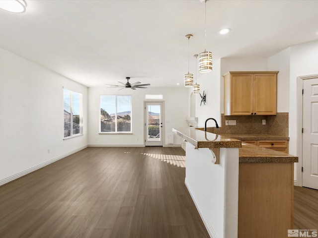 kitchen featuring pendant lighting, dark wood-type flooring, ceiling fan, tasteful backsplash, and kitchen peninsula