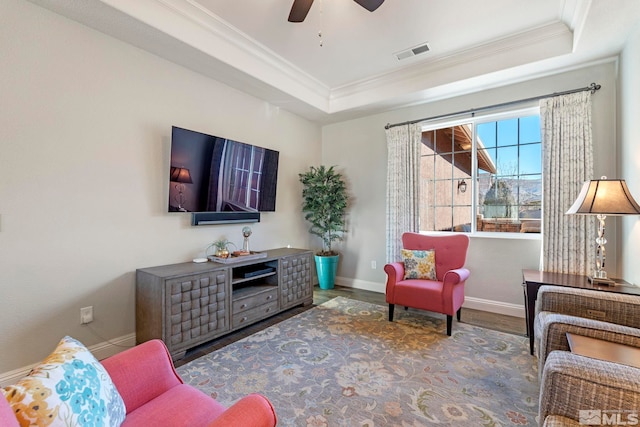 living room featuring wood-type flooring, a tray ceiling, ceiling fan, and ornamental molding