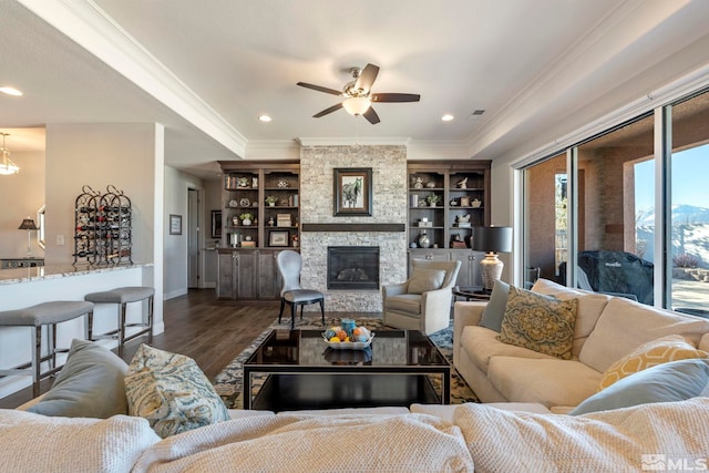 living room with ceiling fan, dark hardwood / wood-style flooring, a fireplace, and crown molding