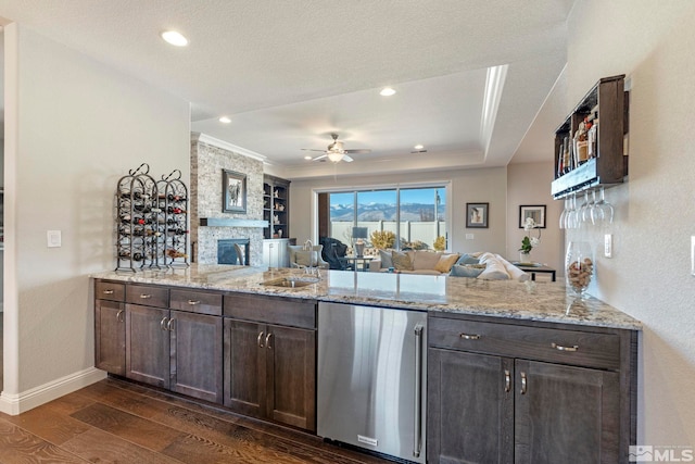 kitchen featuring kitchen peninsula, dark brown cabinets, dark hardwood / wood-style floors, and light stone counters