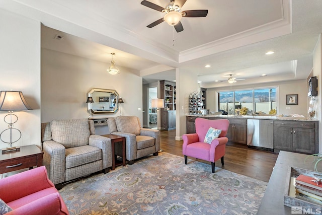 living room featuring a tray ceiling, ceiling fan, dark hardwood / wood-style flooring, and ornamental molding