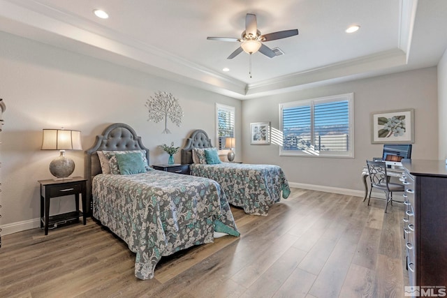 bedroom with a tray ceiling, ceiling fan, wood-type flooring, and ornamental molding