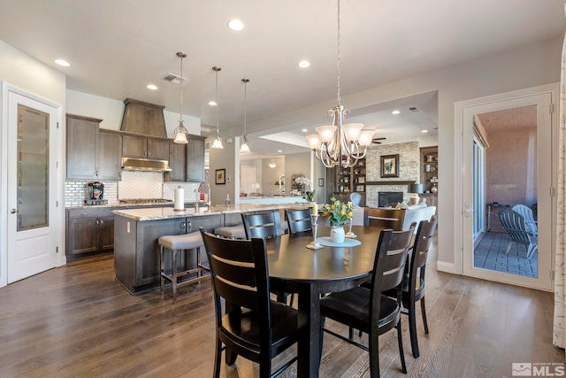 dining area featuring a fireplace, dark hardwood / wood-style floors, an inviting chandelier, and sink