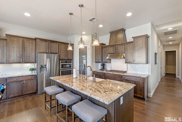 kitchen featuring sink, an island with sink, stainless steel appliances, and decorative light fixtures