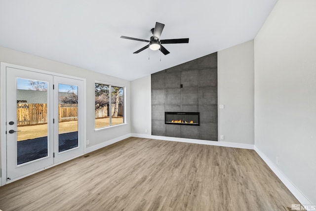 unfurnished living room featuring a tile fireplace, ceiling fan, light hardwood / wood-style flooring, and vaulted ceiling