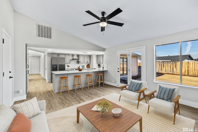 living room featuring ceiling fan, light wood-type flooring, and high vaulted ceiling