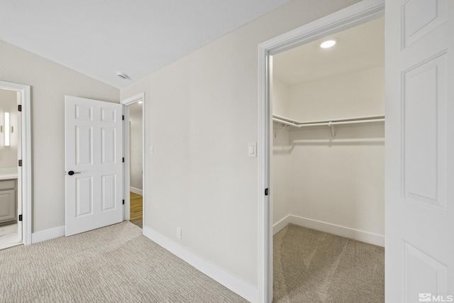 unfurnished bedroom featuring vaulted ceiling, light colored carpet, a spacious closet, and a closet