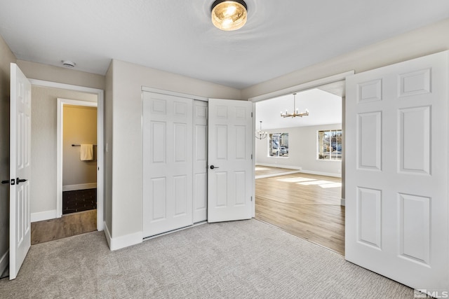 unfurnished bedroom featuring an inviting chandelier, light colored carpet, and a closet