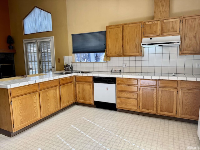 kitchen featuring sink, a high ceiling, tasteful backsplash, kitchen peninsula, and tile countertops