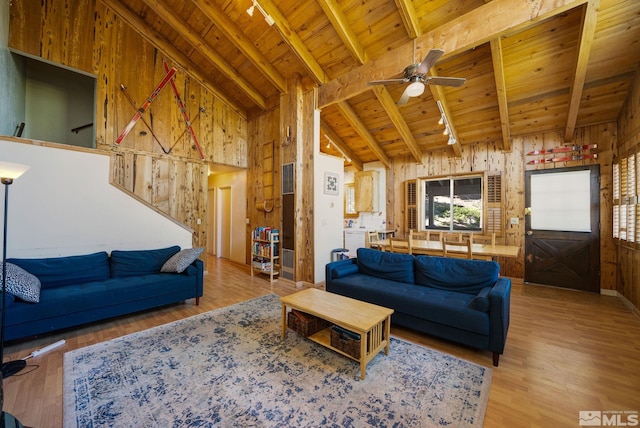 living room with wood walls, wooden ceiling, high vaulted ceiling, track lighting, and beam ceiling