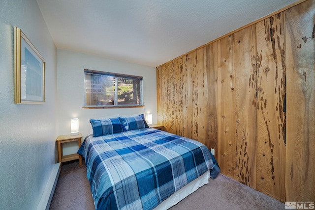 carpeted bedroom featuring a baseboard heating unit and wood walls