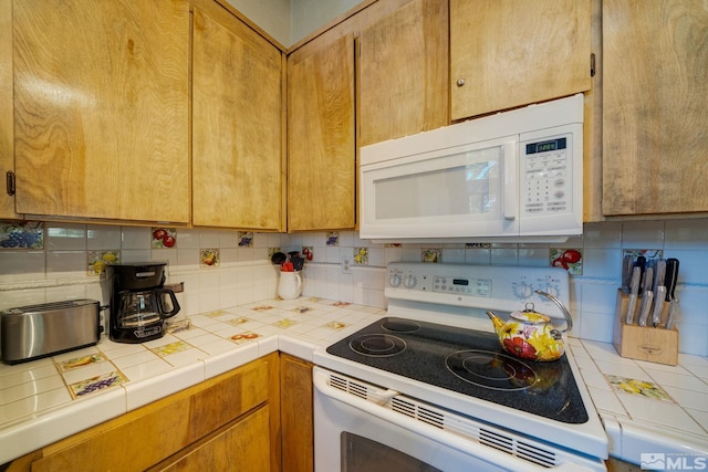 kitchen with tile countertops, white appliances, and tasteful backsplash